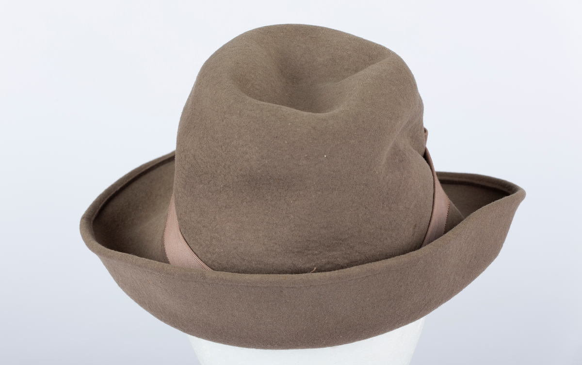 Hatt. Rund hattepull med brem. Bremmen brettet opp. Ripsbånd med sløyfe rundt hattepullen.