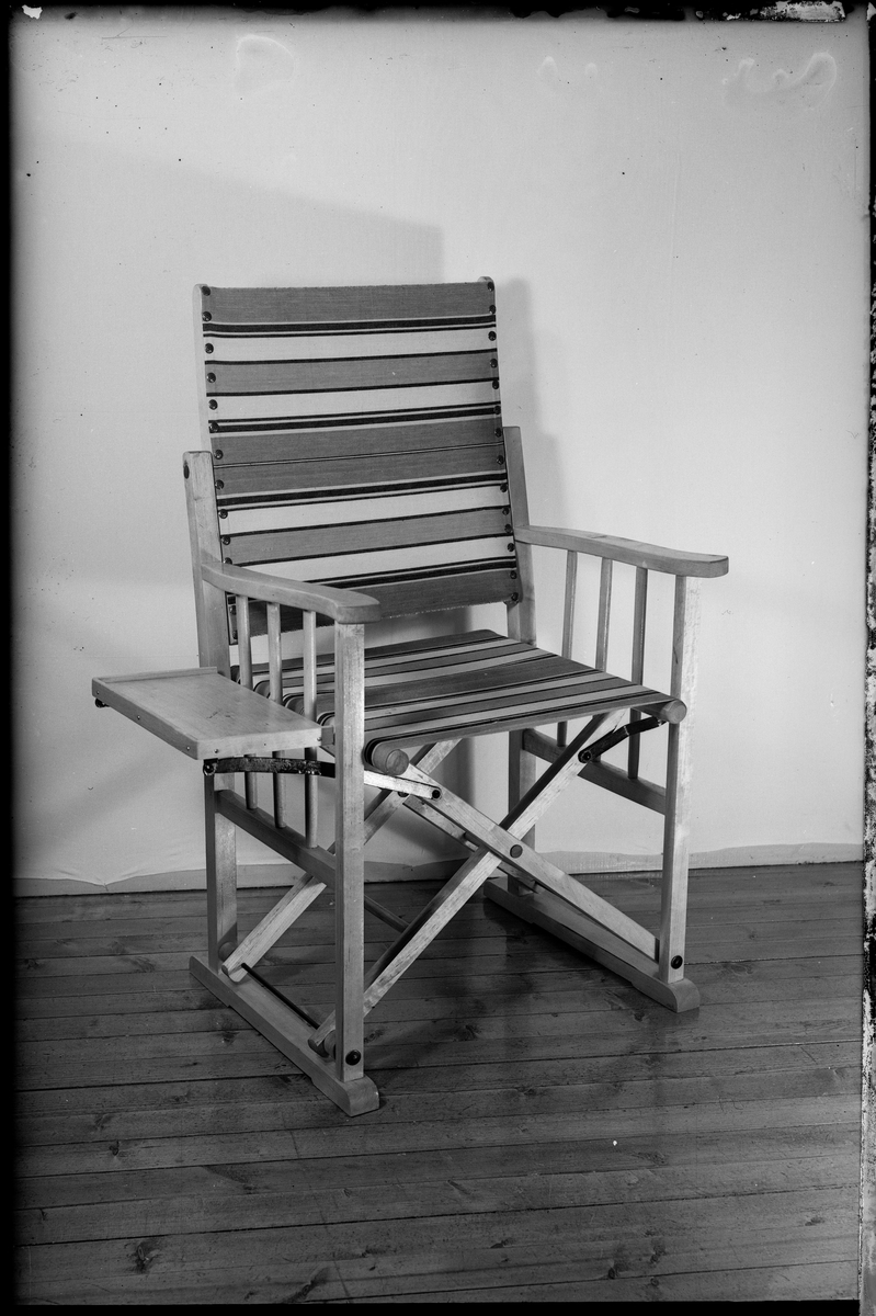 En sammenleggbar stol med bord festet til. På bilde 5 og 6 sitter en mann i stolen.