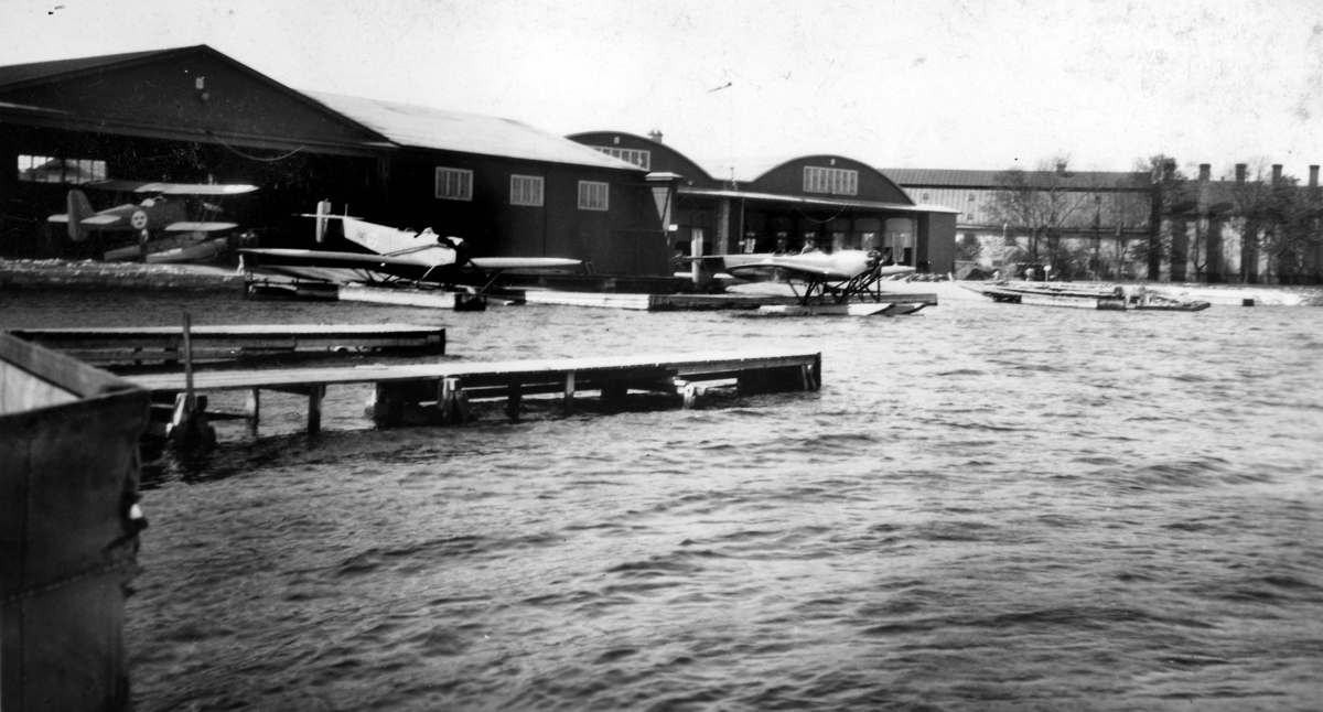 Tre militära sjöflygplan vid brygga och hangarer på Karlskrona flygstation, Stumholmen, 1930-tal. Från vänster flygplan, S 6, S 3 - Heinkel He 2 samt S 5.