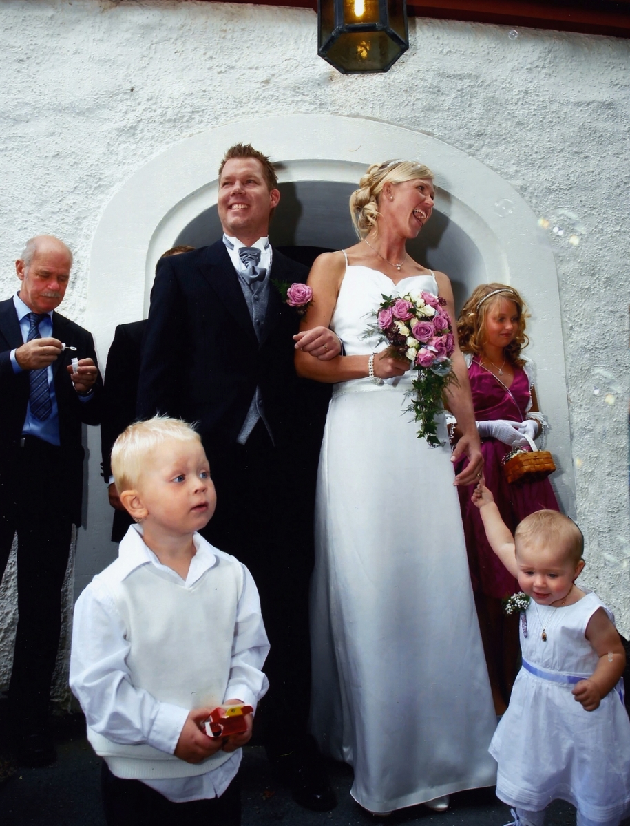 Bröllop 2009-08-26 mellan Mattias Gustafsson och Ingrid (född Paterson) från Olas väg. Brudparet står utanför Kållereds kyrka. Barnen som står framför paret heter Valdemar (född 2007) och Hilma (född 2008). I bakgrunden ses okänd man till vänster och okänd flicka till höger.
