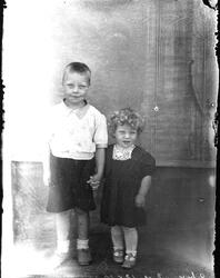 To barn, en gutt og ei jente står oppstilt i et fotoatelier.