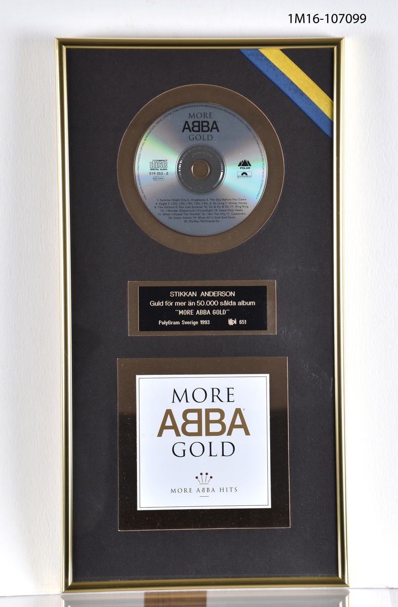 Guldskiva för samlingsalbum "More ABBA Gold". CD-skiva, plakett och konvolut fäst mot guldfärgad ram och svart bakgrund. Guldfärgad ram. Ett blågult band i övrehögra hörnet.

49X25 cm