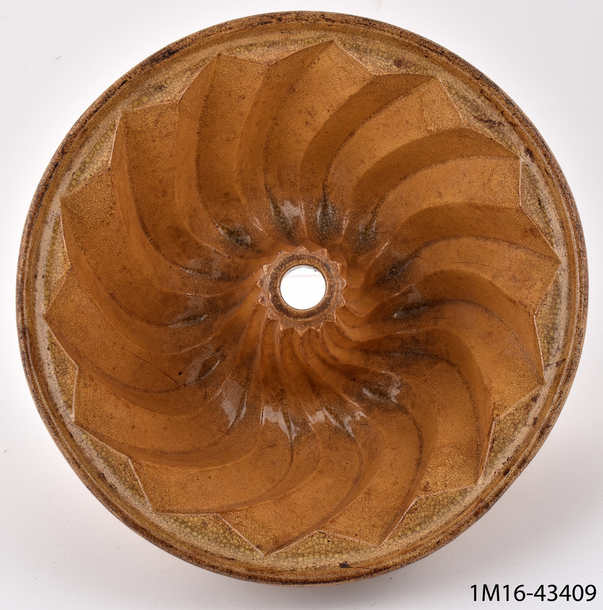 Puddingform, lergods, gulglaserat, diagonalt utgående radier, i mitten uppstående rör.