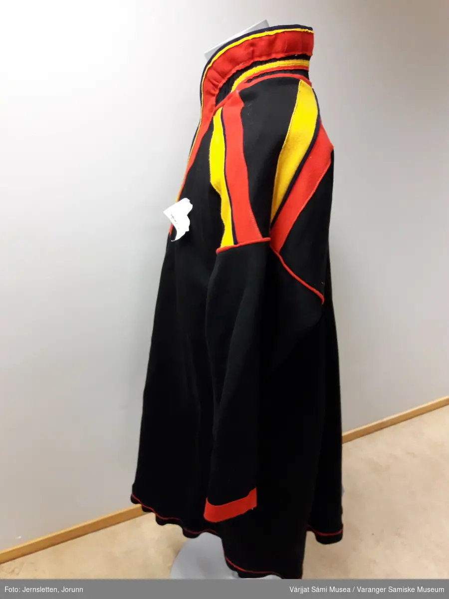 Herrekofte i svart ullklede, med dekorasjoner i rødt og gult klede. Tana-modell, spesielt at det er tre røde striper i ryggen, istedenfor vekselsvis gult og rødt.