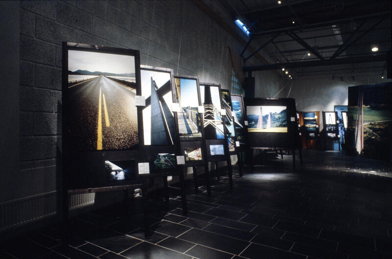 Oversiktsbilde over utstillingen "Eg såg ei bru". Mange sorte stativer med fotografier av bruer.