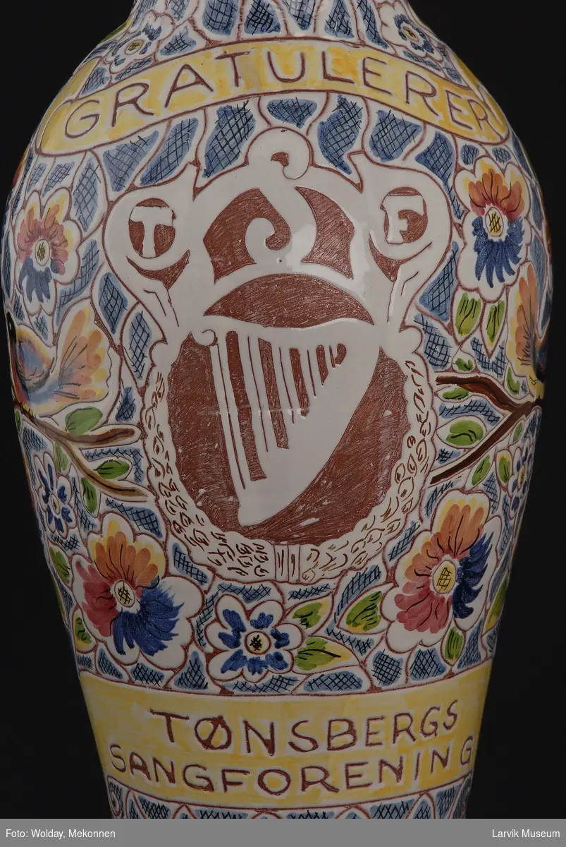 Slank urne smal nederst bredere på midten smalere hals dekorert med fugl, harpe, blomster