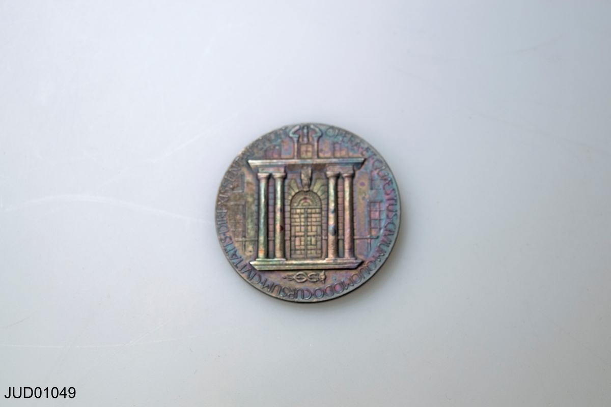 Medalj med profilbild av Eli Filip Heckscher på ena sidan, fasad med pelare på andra.