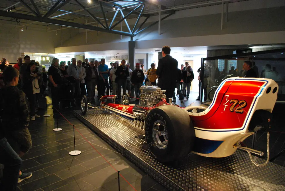 Dragracer tilt ut i resepsjonsområdet på Norsk vegmuseum. Rundt bilen står mye folk.