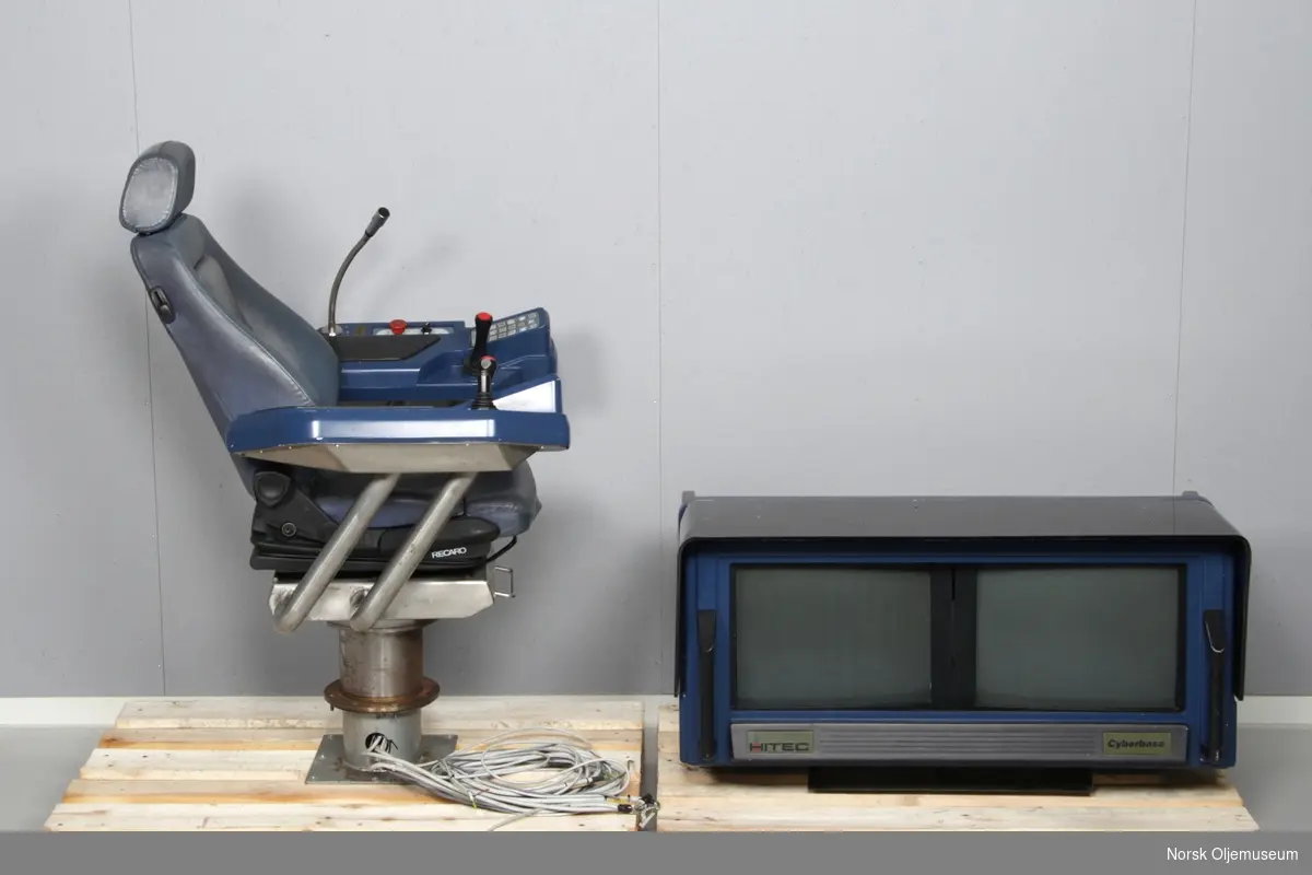 Kontrollutstyr bestående av en operatørstol og et konsoll med dataskjermer.