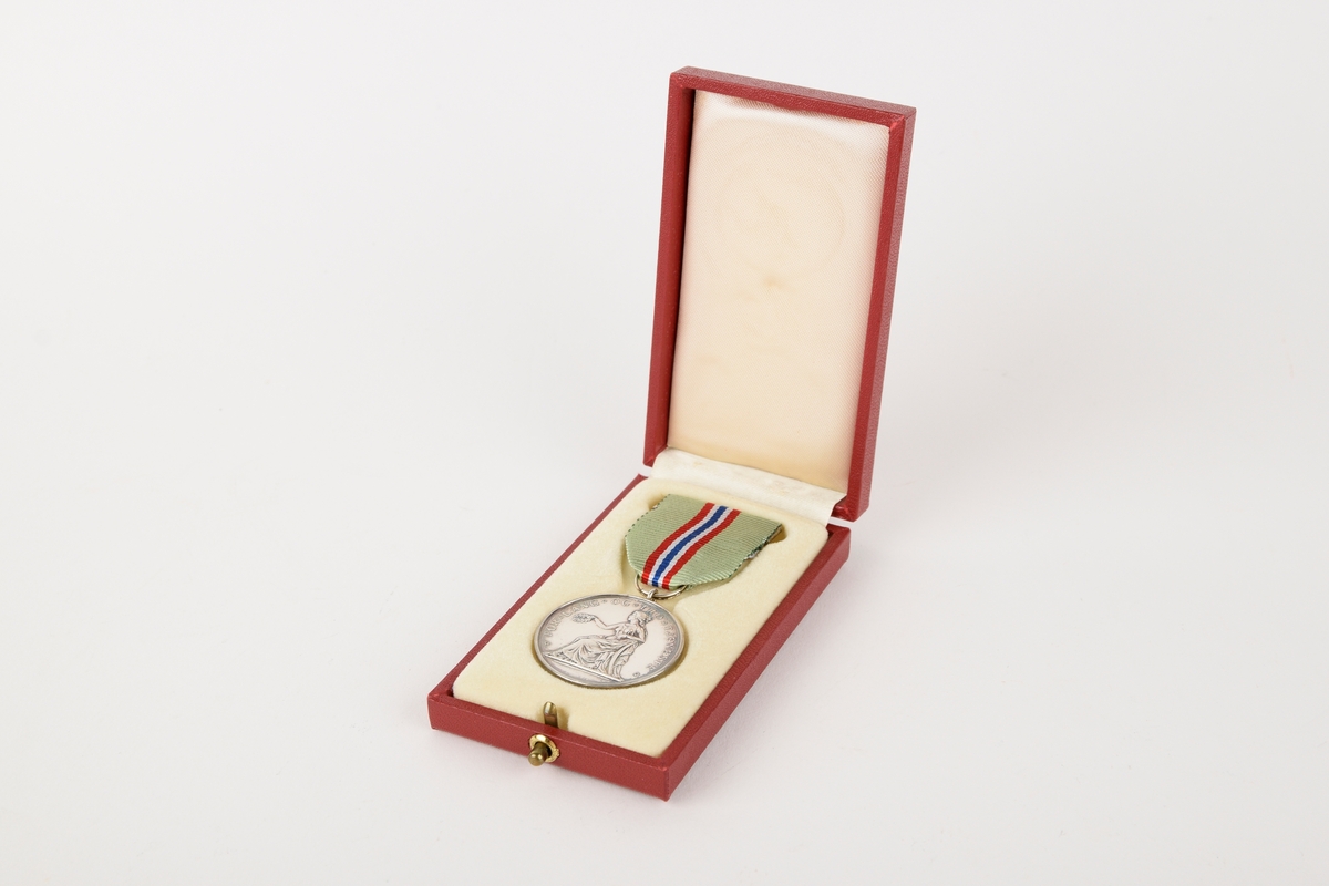 Et eksemplar av "Medaljen for lang og tro tjeneste" i originalt etui. 

Sirkulær medalje med ordensbånd, oppbevart i rektangulært etui.