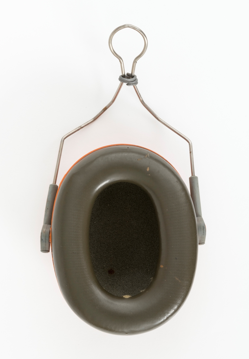 Hørselvern, øreklokke, av typen Peltor H9. Hørselvernet, øreklokka, består av en ovalt formet halvkule av støpt plast med innlegg av skomgummi og en væskefylt tetningsring som omslutter brukerens øre. Innleggene og tetningsringene er utskiftbare. Det er festet en metallbøyle  med glidefeste for høyderegulering til øreklokka. Øreklokkas metallbøyle monteres på hjelmfestet. Det er surret en ståltråd rundt metallbøylen.