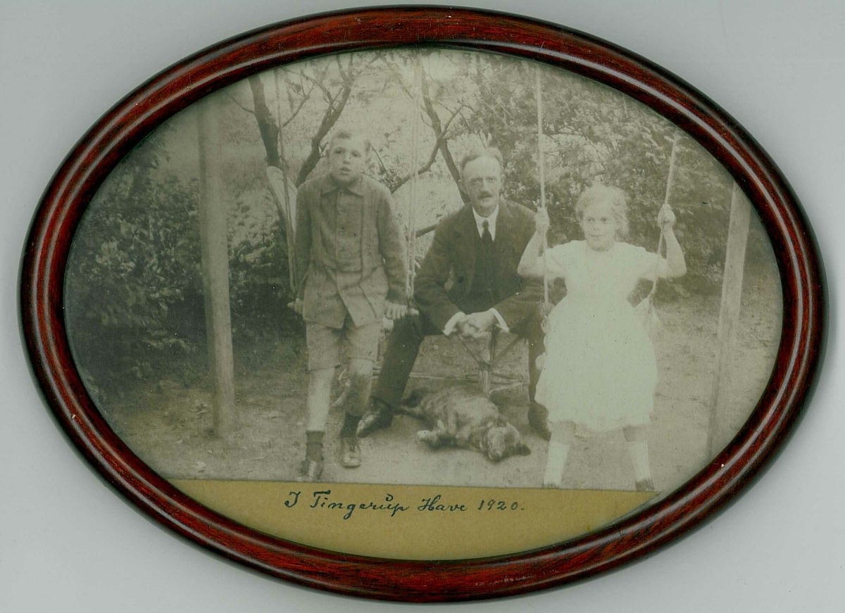 Innrammet bilde. Fotografiet er tatt i Tingerup Have i 1920, og viser Leif Hallesby, hans far Anders Tollef Hallesby og søster kalt "Puta". Det antas at bildet er tatt i Damnark. Leif Hallesbys mor var dansk.