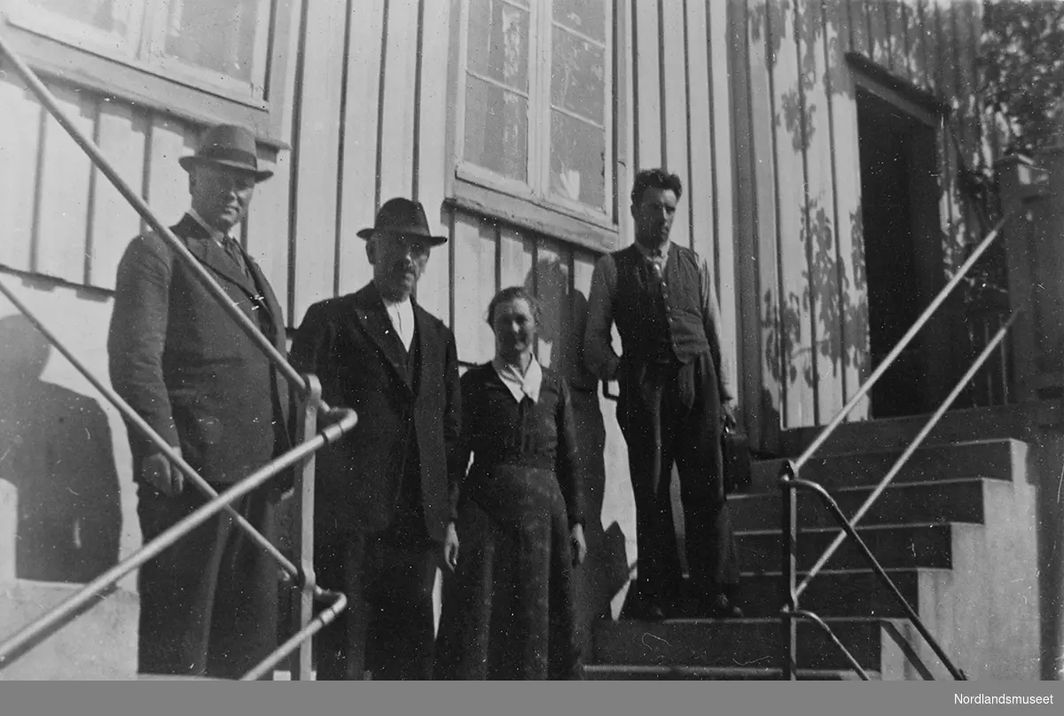 Ole Vatten sammen med to menn og en kvinne. Personene står på ei trapp foran en bolig. Boligen med stående panel og vinduer med små ruter.