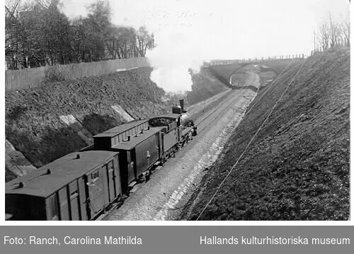 Ett ångande godståg passerar gamla sjukhuset (till vänster) på den nyanlagda sträckningen söderut från Varberg.