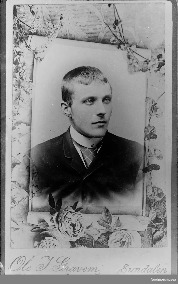 Foto av en av fotografens egne framkalte foto. Har originalt negativ gått tapt? Portrettbilde av ung mann i mørk dress med rutet slips.