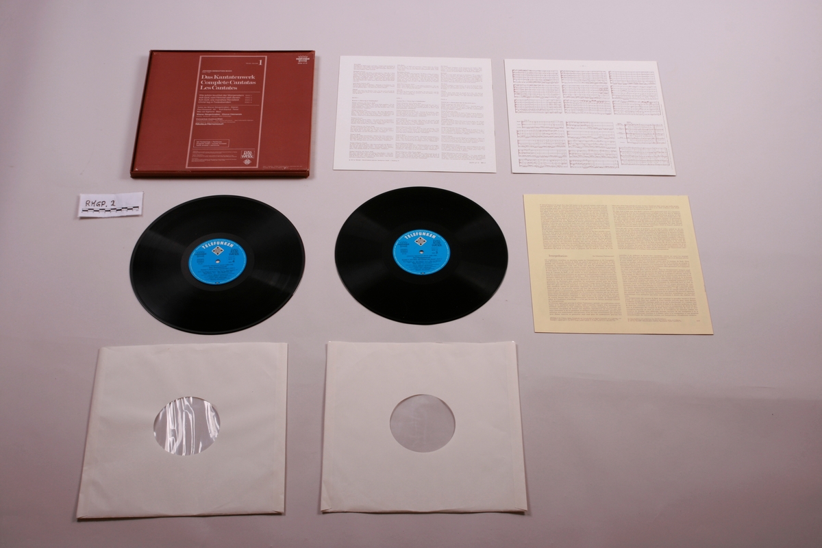 Grammofonplate i svart vinyl og plateboks i papp. Et notehefte og to informasjonshefter.