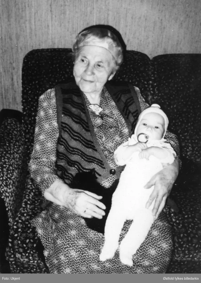 Portrett av Ingrid Sikkeland. Hun er ca. 100 år på bildet. Hun holder et av sine oldebarn. Sikkeland var med og stiftet Varteig Bondekvinnelag, var formann fra 1936-41.