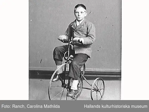 Pojkporträtt. Wilhelm Ranch sitter på en trehjulig cykel.