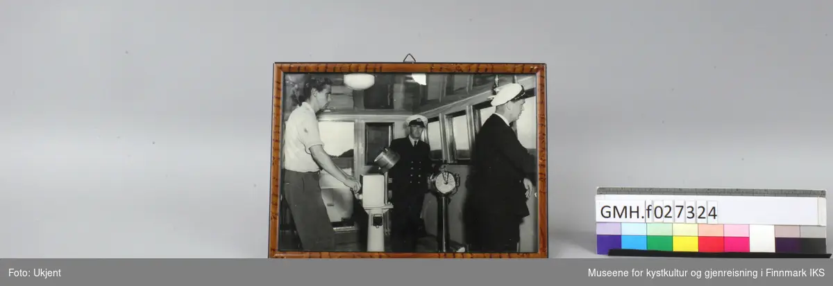 Tre menn står i styrhuset til en båt. To av dem er i kledd i uniform. Mannen helt til høyre er Peder "Pelle" Bang. Bilde er mest sannsynlig tatt ombord på en båt til Finnmark Fylkesrederi og Ruteselskap.