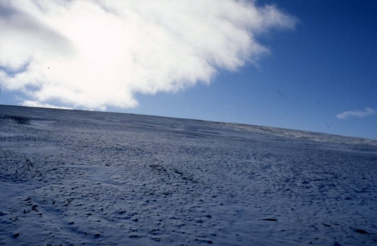 Ett tunt snötäcke på Middendorffberget, Edgeöya. Klarblå himmel med lätta moln.