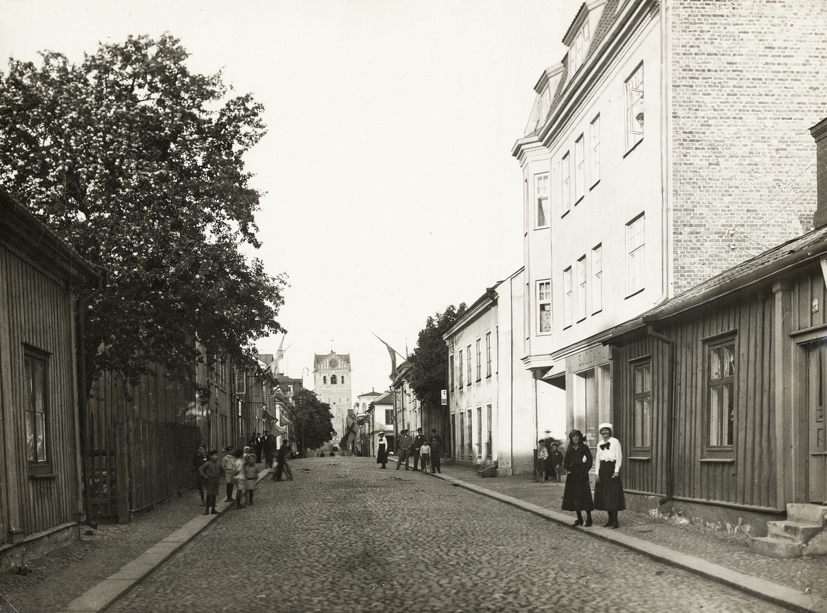 Sandgärdsgatan med blick österut mot domkyrkan, en varm sommardag ca 1920. 
Närmast i bild till vänster kvarteret Blenda (nr 8 a och 7 b) och till höger kvarteret Håkan Sjögren (nr 1, 2 a och 2 b), följt av kvarteret Magnus Smek i bakgrunden.