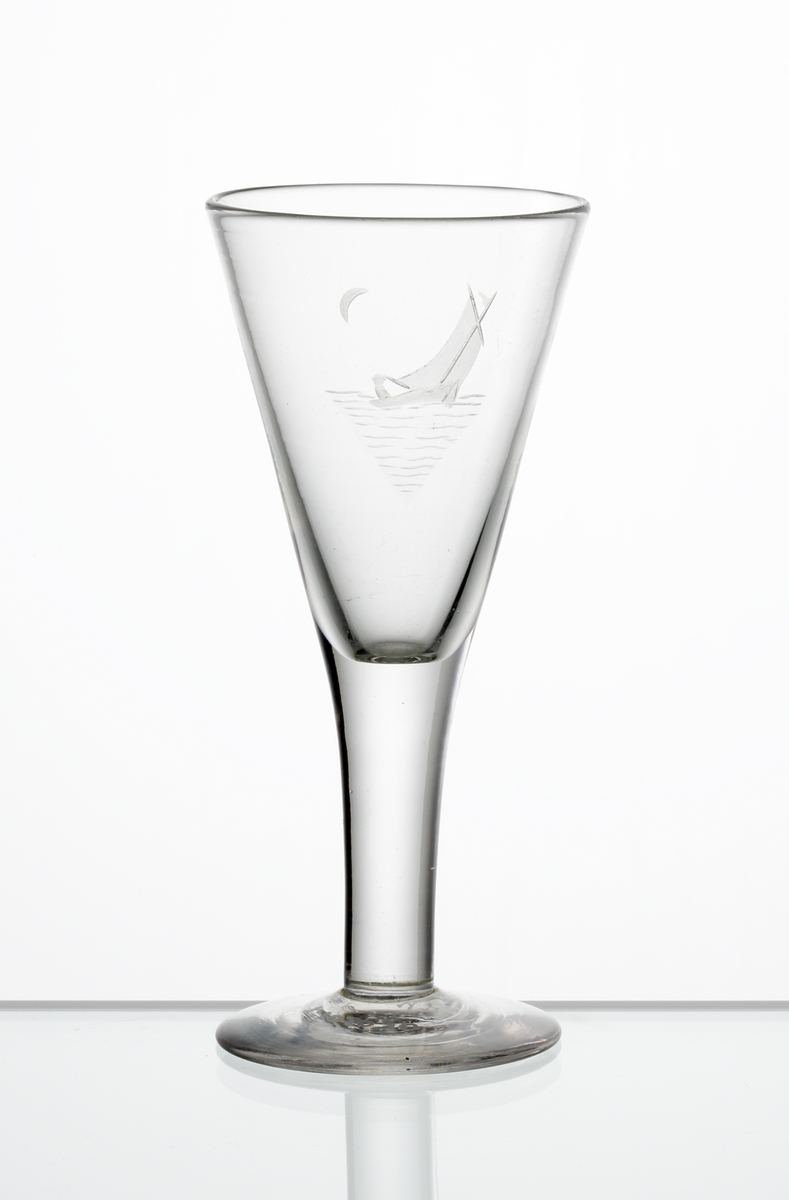 Design: Edward Hald.
Brännvinsglas, konande kupa med graverat motiv i form av en segelbåt med en halvmåne i bakgrunden.