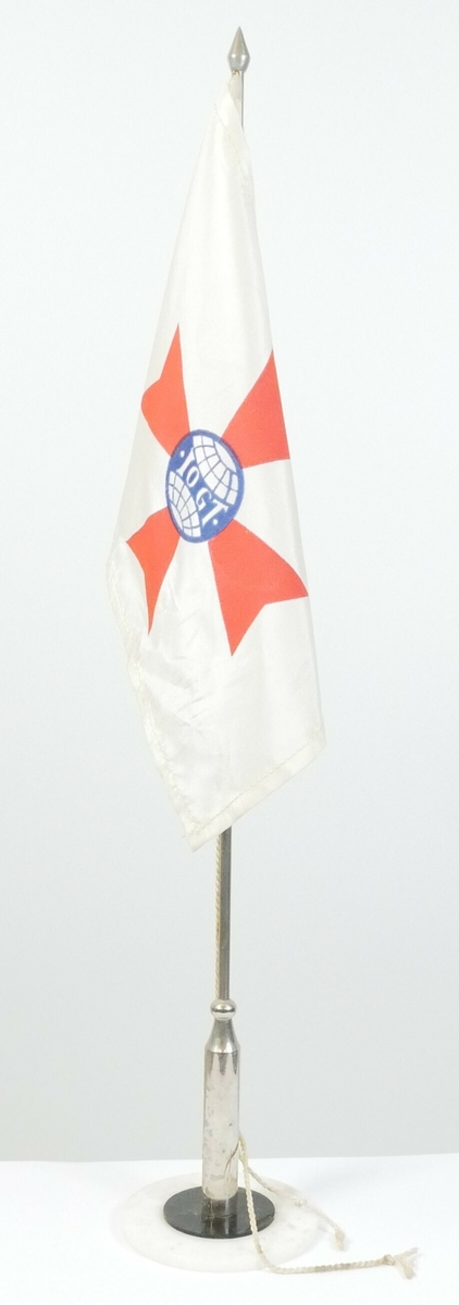 Rektangulært flagg i tekstil festet til en metallstang. Stangen står på en fot i rund hvit plast. 