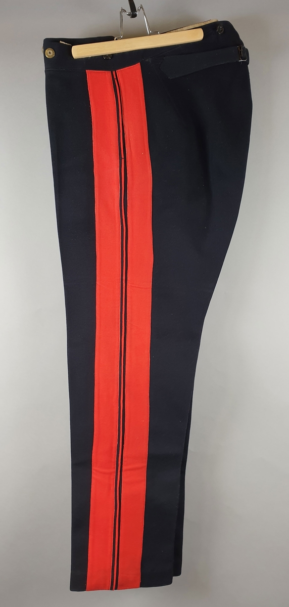 Uniformsbukse med brede røde striper på hver ytterside. Knapper i gylfen og innsydde lommer.