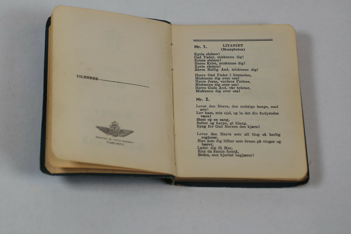 Sangbok fra 2. verdenskrig med vingeemblem og håndskrevet tekst på siste side, skrevet inn med blyant.