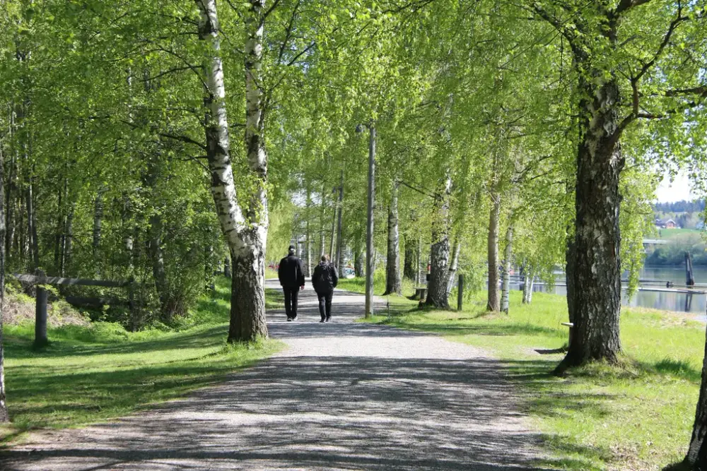 To mennesker går på en turvei langs fløtingsanlegget i elva.