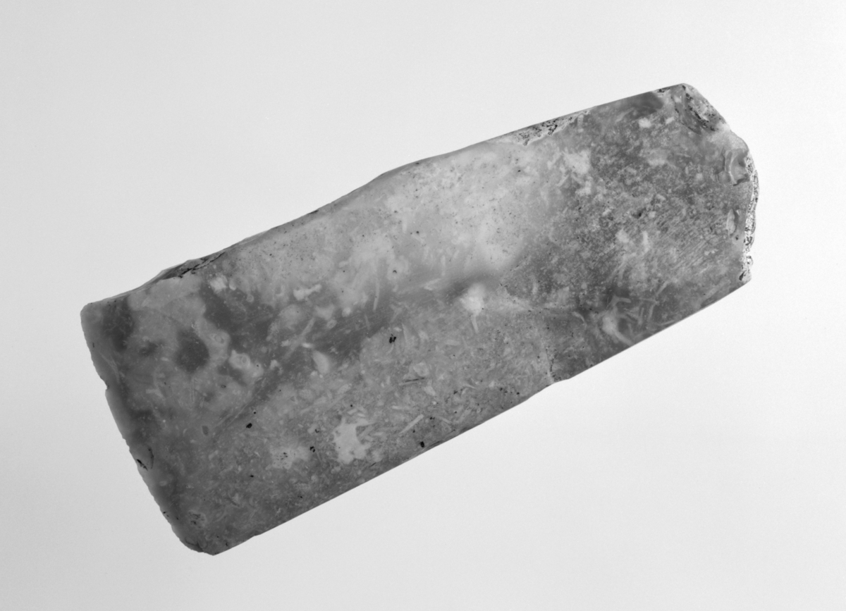 Tynnakket, tynnbladet flintøks fra seinneolitikum med rektangulært tverrsnitt, slipt på alle fire sider, men med huggemerker på tverrsidene. L. 9,1 cm, st.br. 3,7 cm, t. 1,7 cm. Lys grå flint med rester av cortex oppe ved nakken.