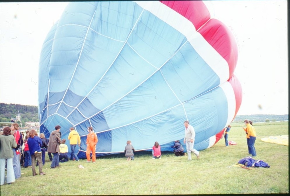 En blå-turkos-vit-röd ballong håller på att fyllas med varmluft.
