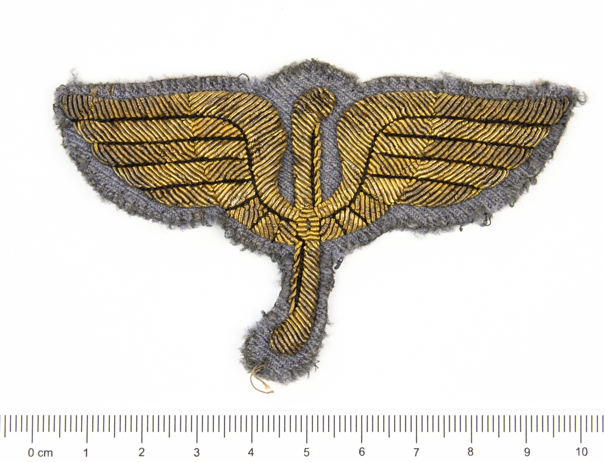Flygförarmärke m/15. Emblemet är sytt med guldbrodyr på grå botten.