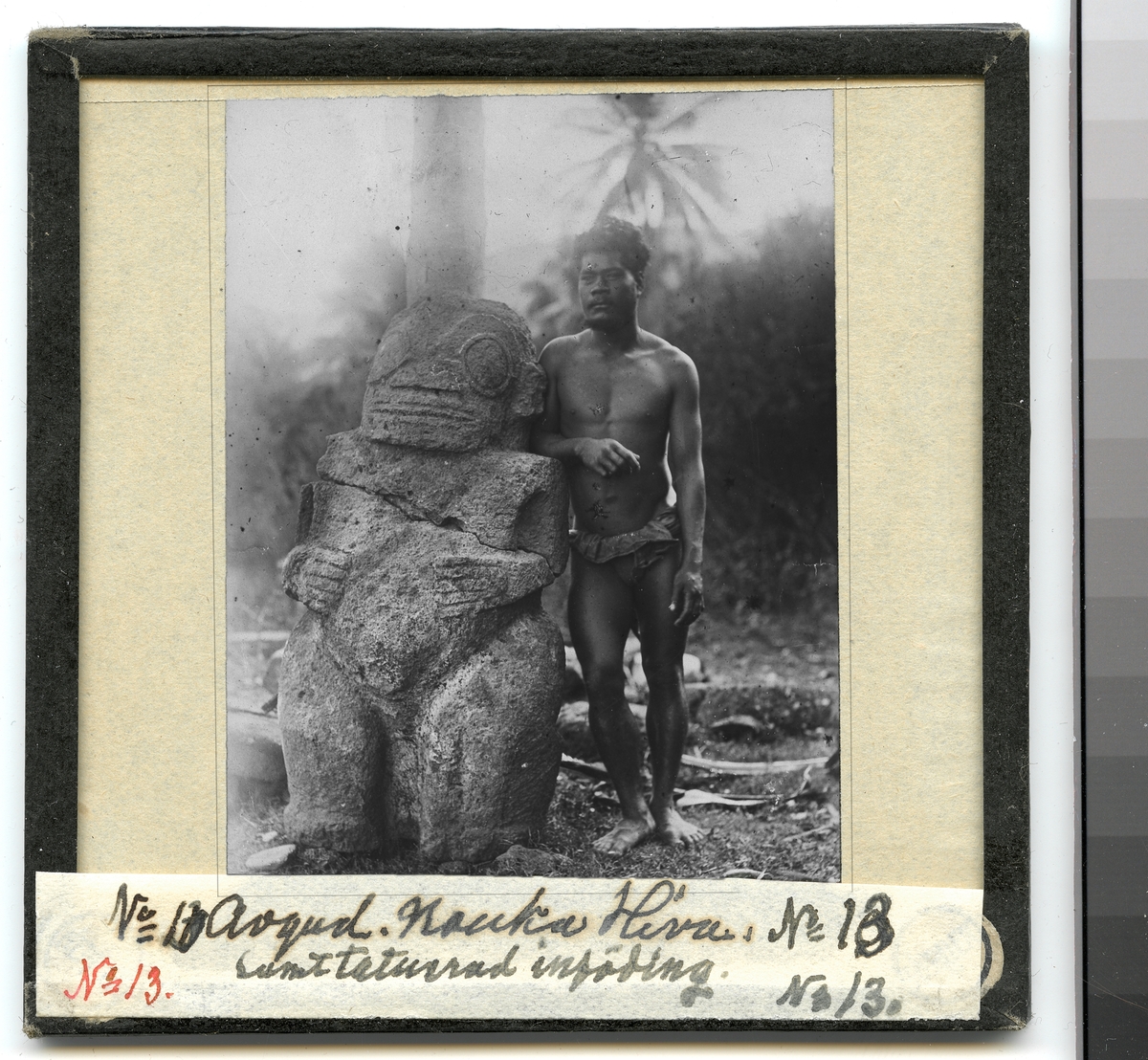 Bilden visar en urinvånare som har tagit uppställning för fotografering bredvid en stenskulptur.