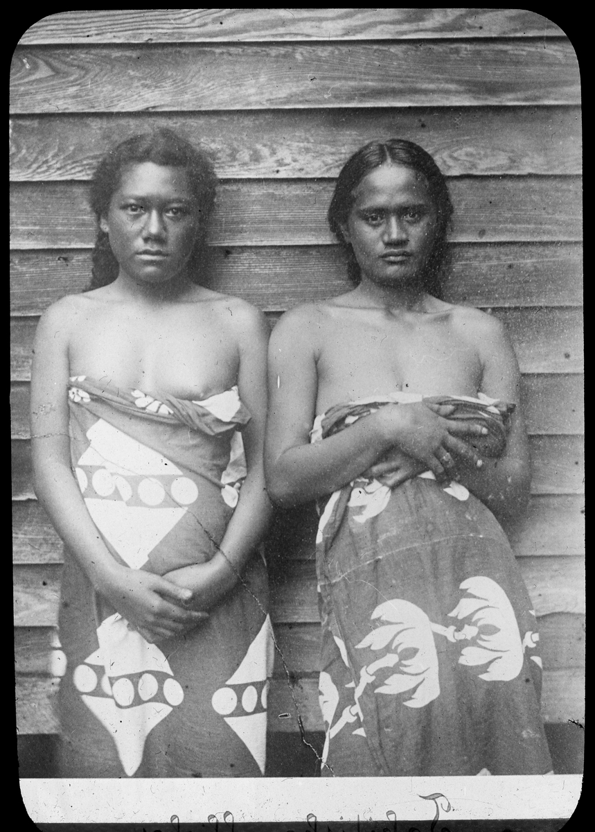 Bilden visar två flickor på Tahiti med traditionella kläder. Enligt Etnografiska Museets bildinformation är det Moea, 18 år och Fatiamai, 15 år från Te Höro, Idaididi.