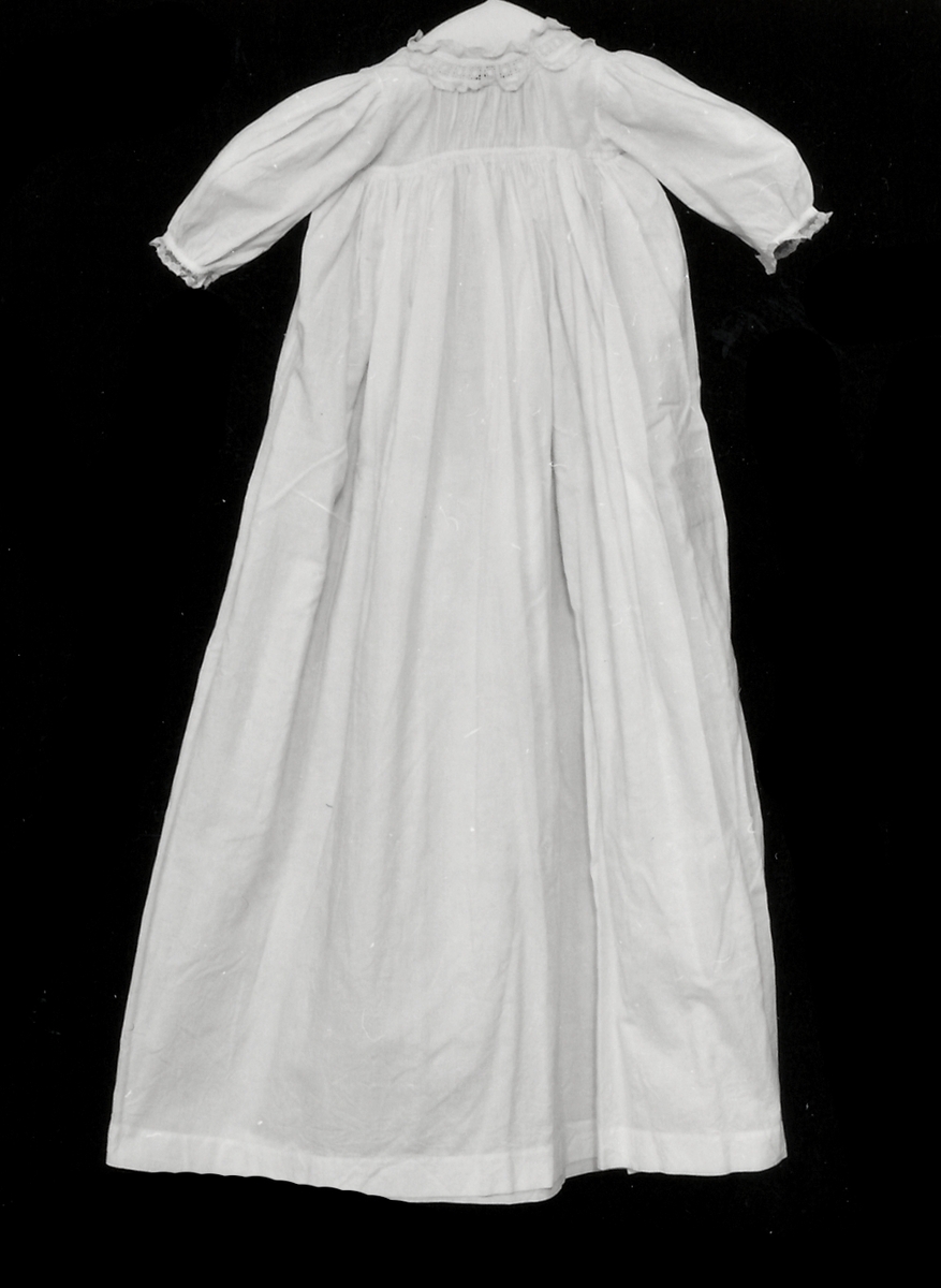 Dopklänning av vit madapolam. Kringa hals och ärmar brodyr.