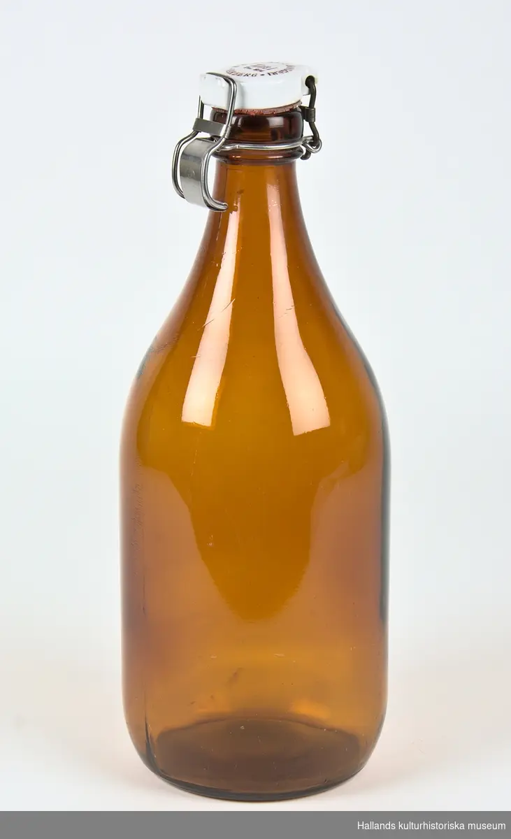 Flaska av brunt glas med vit porslinskapsyl. Text på kapsylen: "A.B RYMANS BRYGGERI * VARBERG * Klass 1. Tel 234.

På botten av flaskan finns stämpeln: S (Sunds glasbruk)