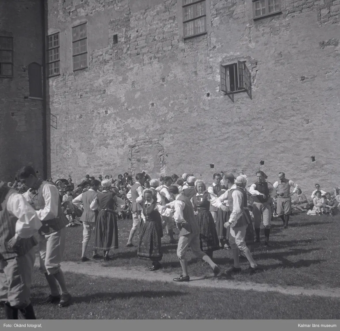 En orkester som spelar violin och folk som dansar i folkdräkter på Kalmar slott.