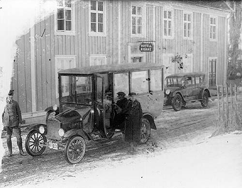 En buss med reg nr F231 står parkerad utanför Hotell Brahe i Gränna. Det är snöslask på vägen. Intill bussen står chauffören Harry Håkansson. Till vänster står en okänd man i chaufförsuniform - möjligen Eklund.