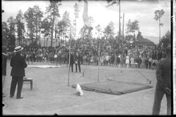 Kretsturnstevne 1930. Mann i øvelse svingstang. Publikum stå