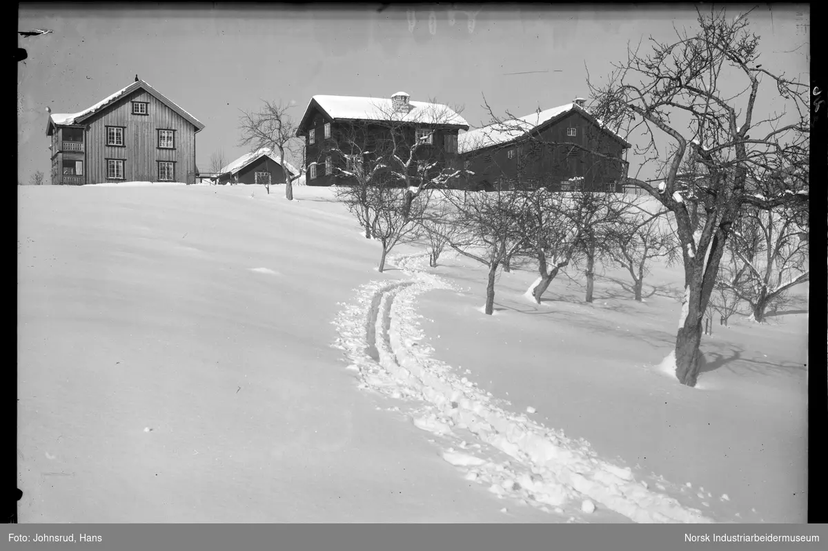 Gårdstun på Ramberg gård i vinterlandskap. To bolighus, stabbur og driftsbygning.