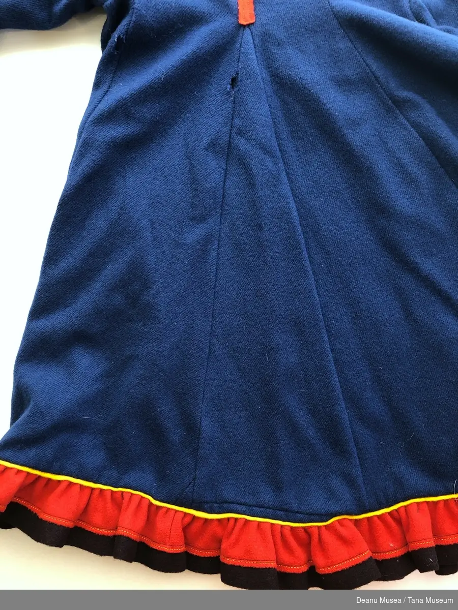 Mørkeblå jentekofte i ullklede fra Alleknjarg med røde pyntekanter. Rød holbi med gul og blå pyntekant.
