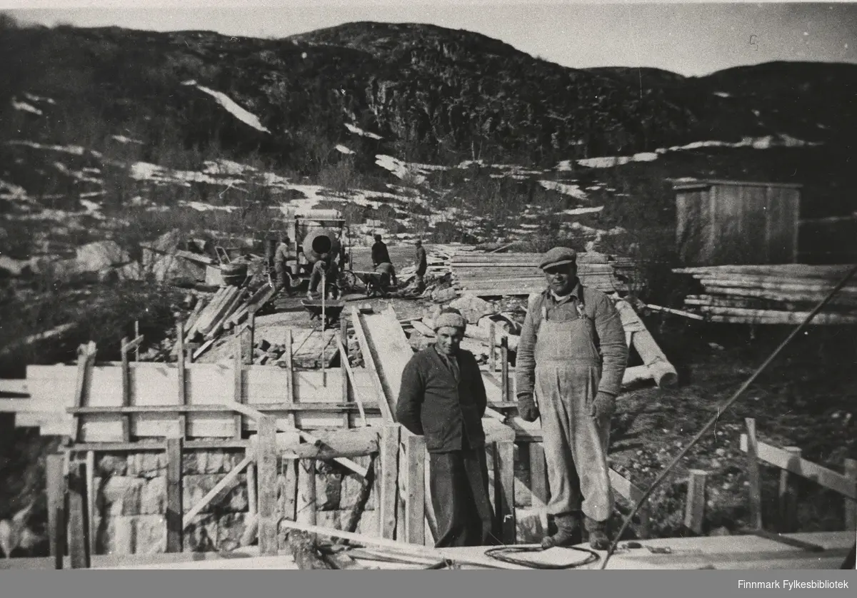 Krigskadeutbedringer i Finnmark 1946. Portrettfotografi av to menn, Andreas Lavde og Johan Losoa ved den påbegynte Reppen bru.