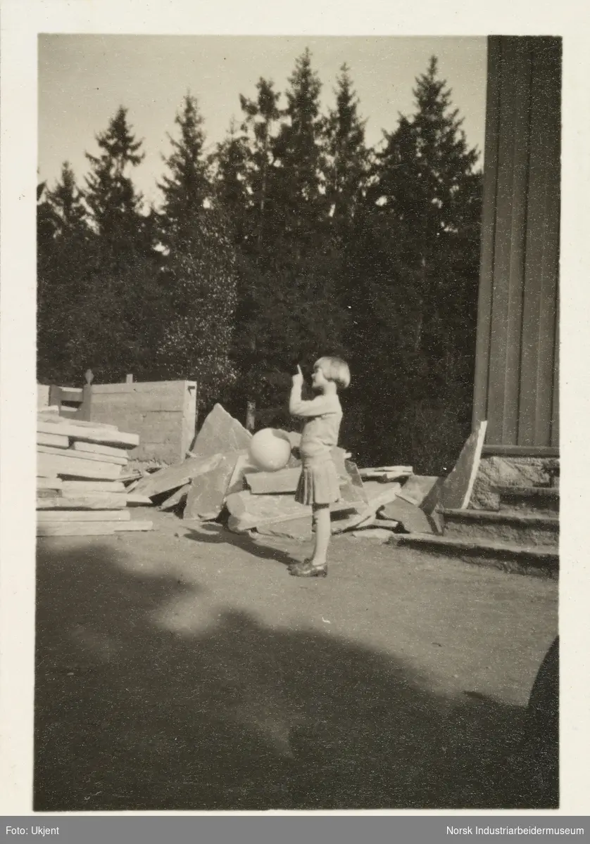 Sommeren 1931, Gullia og Fagerli. Jente i skjørt med bolleklipp holder en ballong i den ene handen og retter pekefingeren med den andre
