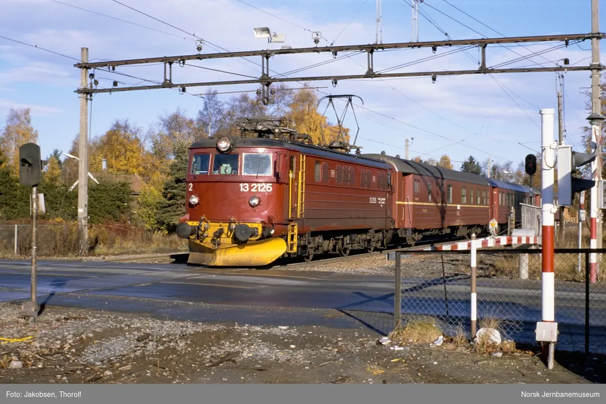 Elektrisk lokomotiv El 13 2125 med persontog på planovergangen ved Ås stasjon