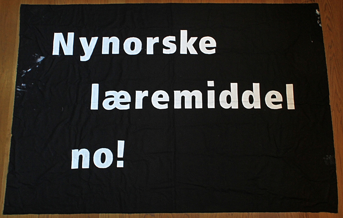 Banner frå arkivet til Norsk Målungdom. På banneret står teksten: "Nynorske læremiddel no!". Det er truleg at banneret har vore i bruk under ein aksjon for Norsk Målungdom.