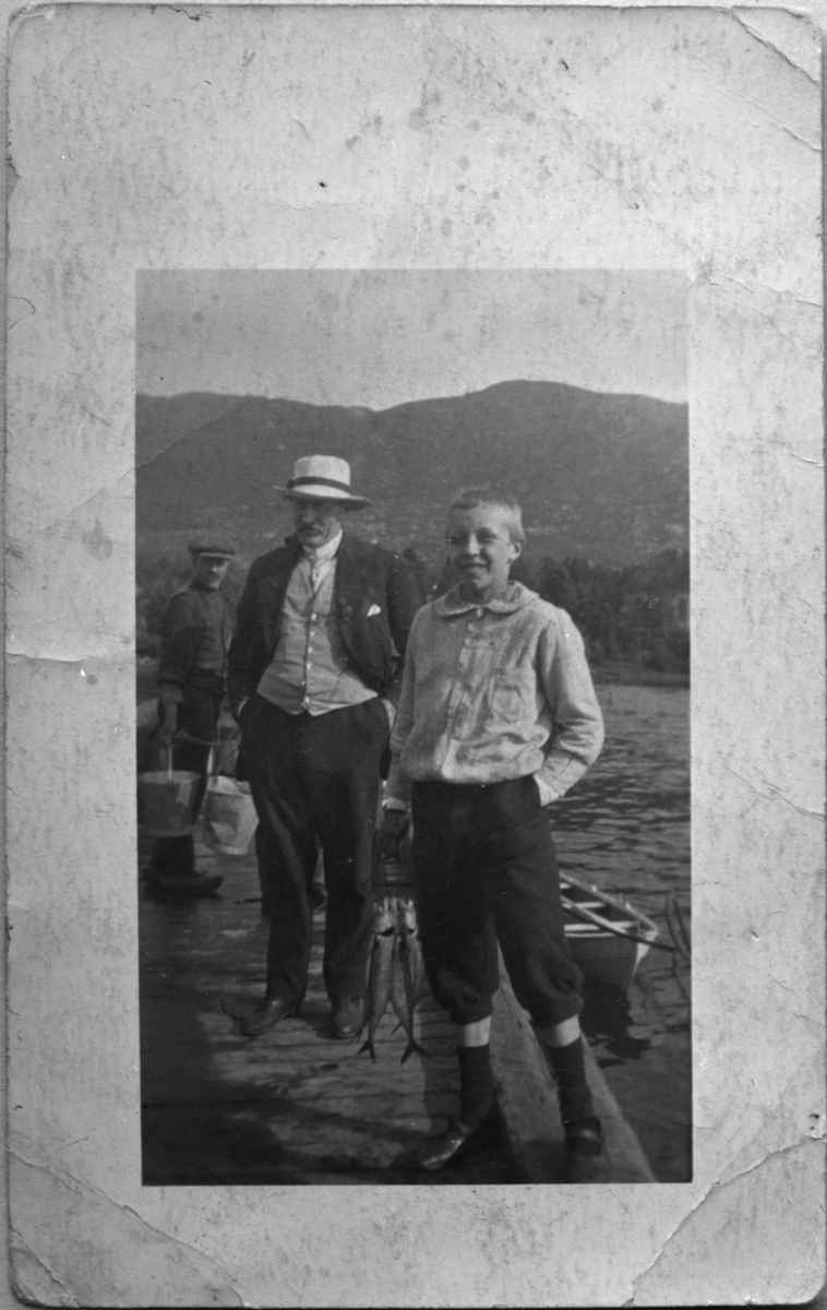 Heimkomst til Plassabryggjå i Vikebygd etter vellukka fisketur, ca. 1920. Frå venstre: Ole Veastad, Helge Alne og ein ukjend besøkande bygut.