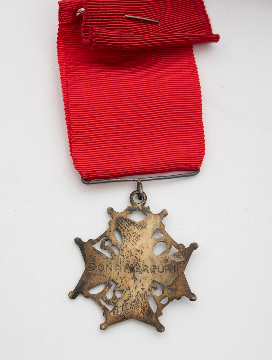 Ordensmedalje/-nål festet til rødt medaljebånd, som igjen er festet til rødt bånd til å ha rundt halsen.