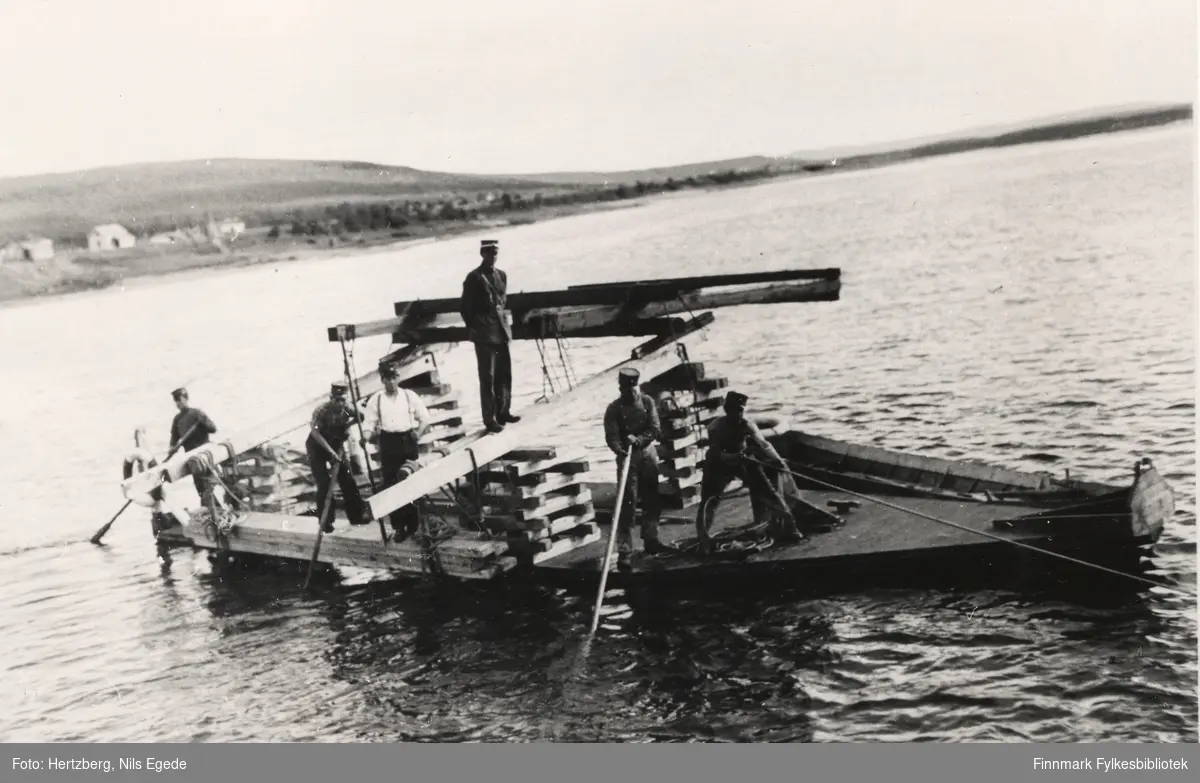 Brubygging over Tanaelven. Seks menn med løytnant Ramsli i spissen fører bukkene på plass i Tanaelven. Året er 1939.