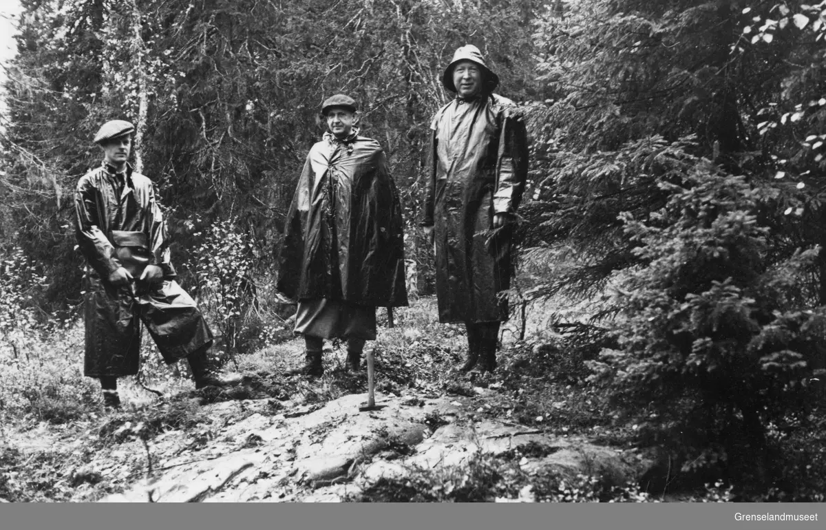 Tre menn i skogen ved et bart berg, en hakke tyder på at de driver med prøvetaking, Rana september 1937.